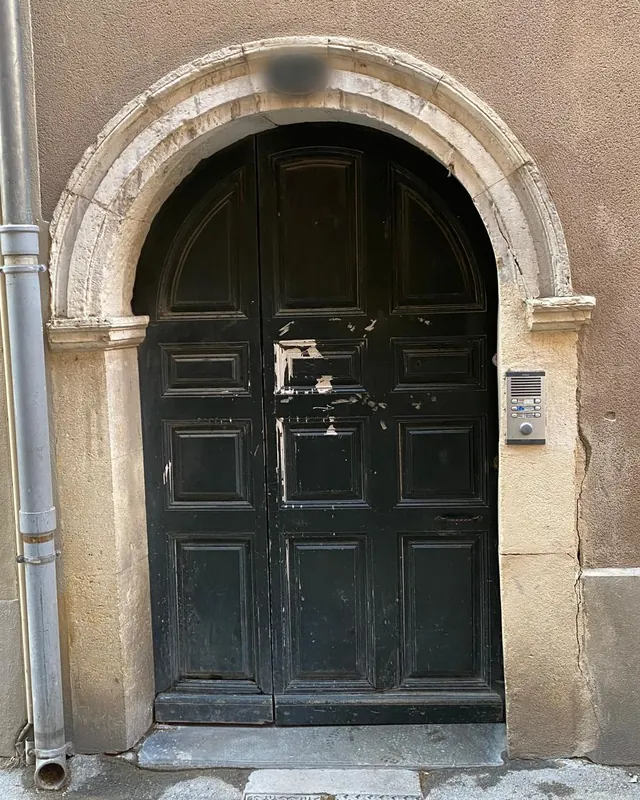 Avant : ancienne porte en bois abîmée sous une arche en pierre
